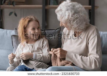 Clever with needle like granny. Cute preteen girl enjoy knitting imitate skilled retired grandma make woolen clothes following her example. Old nanny explain little girl basics of needlework technique Royalty-Free Stock Photo #2321830733