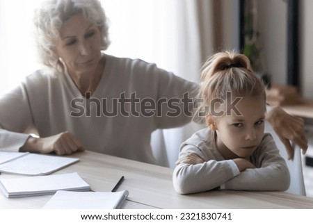 Upbringing difficulties. Old lady teacher look with reproach at disobedient pupil girl turning away refusing to study. Annoyed older grandma talk to obstinate grandchild try to convince she is wrong Royalty-Free Stock Photo #2321830741
