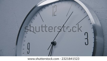 Static shot of white watch with metal frame hanging on the wall and showing time. Walking wall clock in office with modern design. Strict clock with fast running time pointer. Close up. Royalty-Free Stock Photo #2321841523