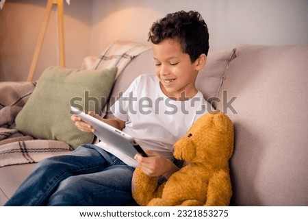 Portrait of charming happy small boy plushie watching movie wear white shirt stylish bright child room interior furniture decoration
