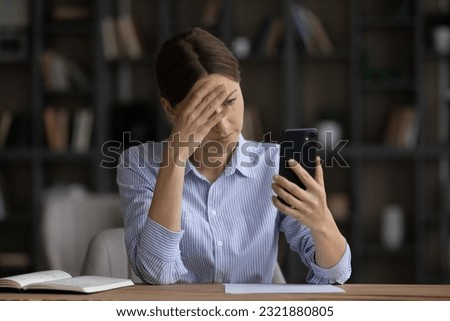 Frustrated young woman looking at cellphone screen, feeling nervous of getting message or email with bad news, upset female entrepreneur manager employee having problems with gadget, annoyed by spam. Royalty-Free Stock Photo #2321880805