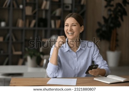 Excited sincere young businesswoman manager employee looking in distance, sitting at workplace with cellphone in hands, feeling joyful dreamy of getting message with good news, thinking of new offer. Royalty-Free Stock Photo #2321880807