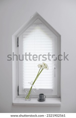 Good morning, wake up concept. A cup of coffee on a windowsill by the window. Composition with flowers in a cozy minimalist white living room interior. Concept of morning routine, decor and comfort