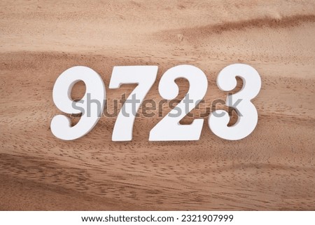 White number 9723 on a brown and light brown wooden background.
