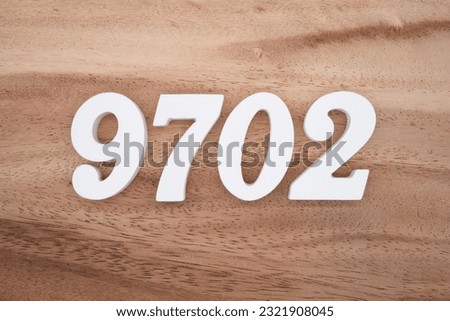 White number 9702 on a brown and light brown wooden background.