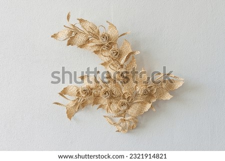 Decoration of straw on a white background. Branch with leaves and flowers is made of straw. Decor. Closeup