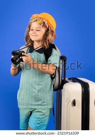 Traveler tourist kid boy 7-8 years old on isolated studio background. Travel on weekends getaway. Independent kid boy with big travel bag.