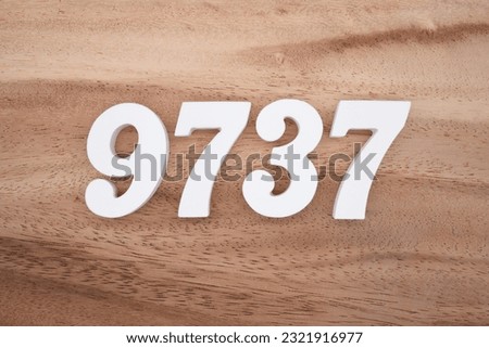 White number 9737 on a brown and light brown wooden background.
