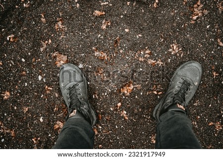 Feet in black sand with golden autumn leaves.