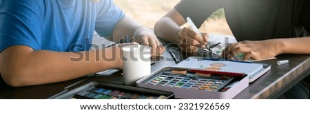 Closeup image of watercolor painting, drawing and coloring with watercolor on table of asian boys at home, cropped shot, concept for recreational activity of children around the world.