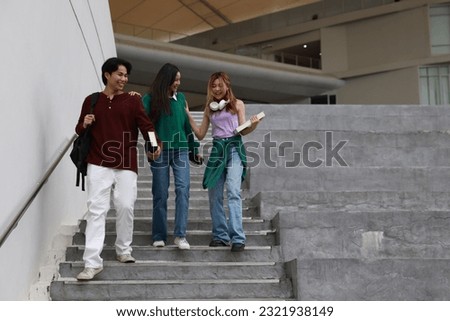  Group of happy young friends sitting on college campus and talking. A cheerful group of smiling girls and guys feeling relaxed after an exam outdoors "SSTKUNIVERSITY"