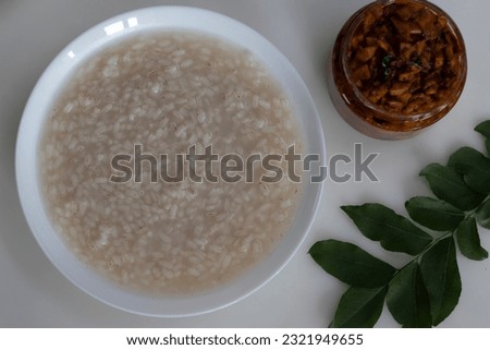 Kanji and Kadumanga. Rice gruel prepared with Kerala Matta rice. Shot with Kerala style cut mango pickle on a white background.