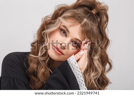 young girl in black school dress poses as doll on white background in studio