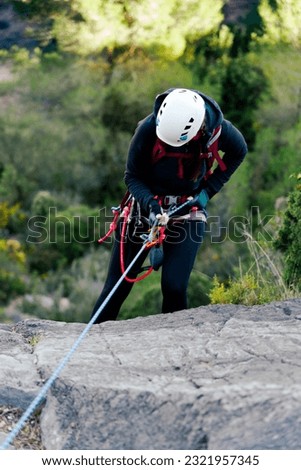 Woman in white helmet rappeling. Royalty-Free Stock Photo #2321957345