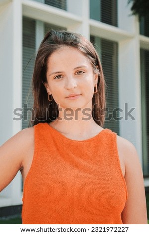 Vertical portrait of confident serene woman posing for photo standing with hand on hip. Serious young Caucasian teenage female looking at camera having relaxed emotion and gentle facial expression