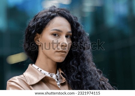 Portrait of mature adult business woman outside office building, close up Latin American woman with curly hair looking at camera, woman boss financier in business clothes. Royalty-Free Stock Photo #2321974115