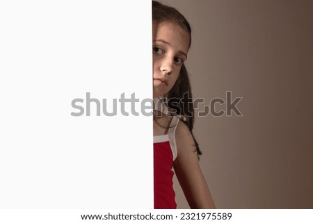 Cheerful young girl behind white blank banner or empty copy space advertisement board on brown background, Copy space for text or design.