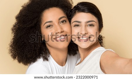 Close up portrait of smiling multiracial diverse girlfriends isolated on yellow studio background. Happy multiethnic female friends laugh take selfie picture together. Diversity, friendship concept.
