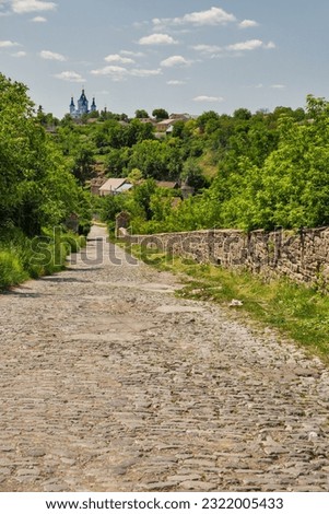 Cobblestone medieval road in Kamianets-Podilskyi Old Town, Ukraine. Church of St. George in the background.