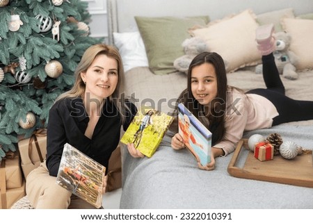 mother and daughter hold photo canvas at Christmas.