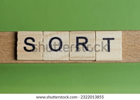 word sort made of small gray wooden letters on a green paper background