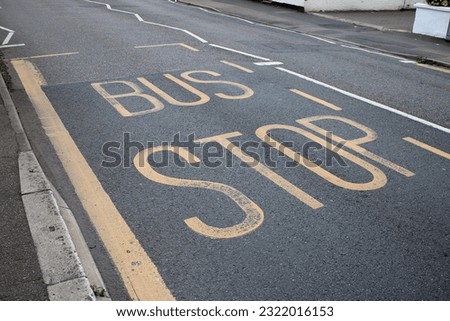 Yellow road markings "Bus Stop" UK painted on a asphalt road Royalty-Free Stock Photo #2322016153