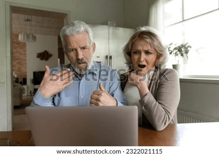 Unhappy mature couple spouses look at laptop screen shocked by bad unexpected news or notice online. Upset old Caucasian man and woman talk on video call stunned by negative message on computer. Royalty-Free Stock Photo #2322021115