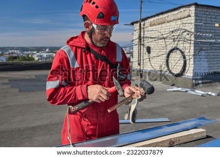 Rope access.  A roofer works with tin on the roof. Worker wearing protective helmet.