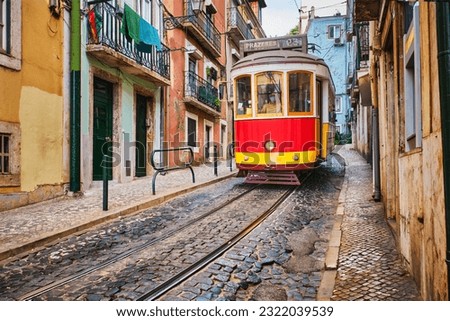 Famous vintage yellow tram 28 in the narrow streets of Alfama district in Lisbon, Portugal - symbol of Lisbon, famous popular travel destination and tourist attraction Royalty-Free Stock Photo #2322039539