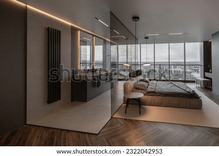 cool expensive interior design of room in prestigious luxury hotel with dark tones with modern LED lighting and stylish furniture. the area with a sink is separated by dark glass from the bedroom Royalty-Free Stock Photo #2322042953