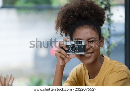 A beautiful African American girl taking photos with a retro film camera.
