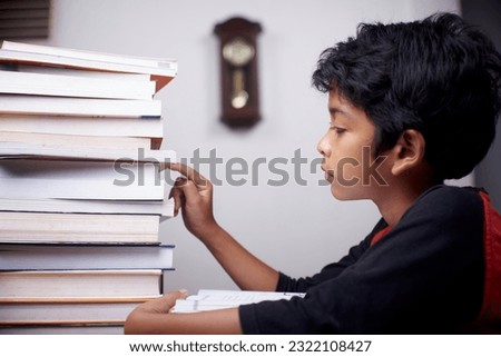 Little boy reading piles of books at home