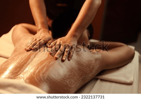 Masseuse hand applying salt scrub on back customer at cosmetology spa centre. Relaxation man customer get service skincare scrubbing massage with masseuse in spa salon. Selective focus. Royalty-Free Stock Photo #2322137731