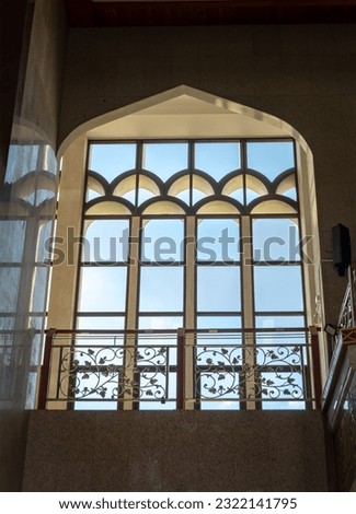 The sunshine lights through the glass window frame and there have wrought iron decorative rails patterns in the corridor. Architecture of Interior Building is built for the Islamic Affairs.art concept Royalty-Free Stock Photo #2322141795