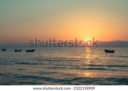 A picture of a fishing boat in the middle of the sea at sunrise