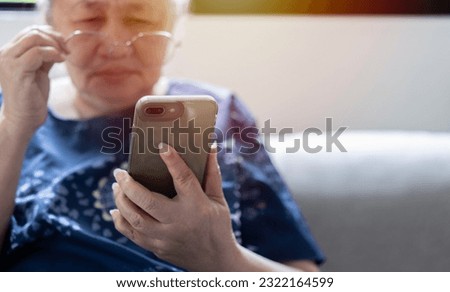 Asian senior fatigue woman taking off eye glasses during using smartphone after surfing internet or social media at home. Elderly retired male eyesight problem or blurry vision from old aged Royalty-Free Stock Photo #2322164599