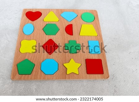 Wood Puzzle with Geometric Shapes. Wooden kids geometric puzzle with the object removed and put beside the puzzle. Montessori wooden toys for children. Sorter for different shapes.
