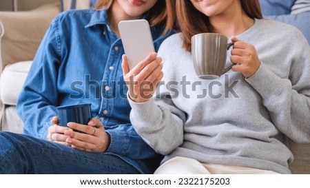 Closeup image of a young couple women using and looking at mobile phone together