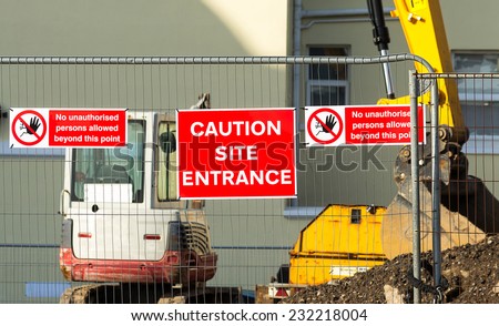 Caution sign at entrance to construction site.Red plaque hanging on the fence in the middle between the two arrays speaking about the ban on entry to the site.
