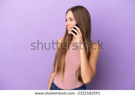 Young Lithuanian woman isolated on purple background keeping a conversation with the mobile phone with someone
