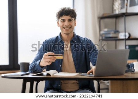 E-Commerce Offer. Cheerful Middle Eastern Businessman Using Credit Card And Laptop Shopping Online Sitting At Workplace In Modern Office. Joyful Entrepreneur Making Payment Via Online Banking