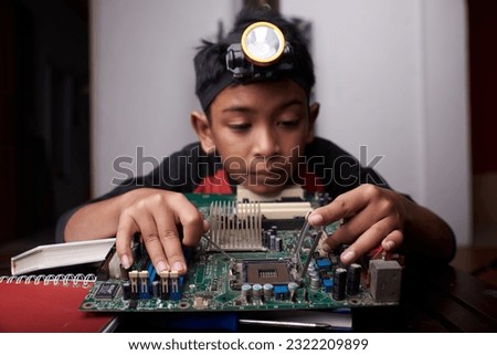 Young boy holding motherboards, learning computer hardware at home