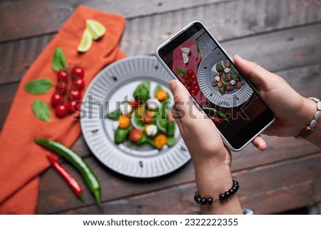 High angle view of photographer making photo of vegetable salad on mobile phone