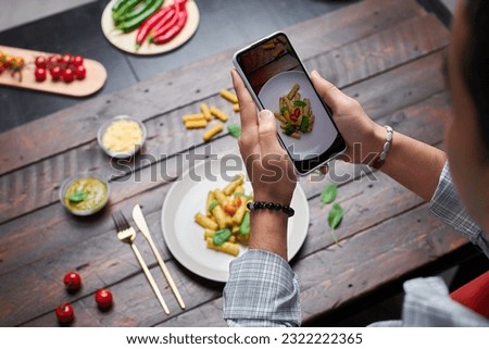 High angle view of photographer making photo of pasta on smartphone for his food blog