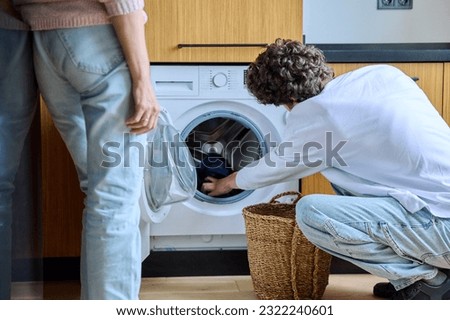 Young guy at home using washing machine with basket of dirty things Royalty-Free Stock Photo #2322240601