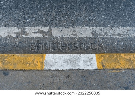 Road sign, white and yellow strip painted on asphalt surface road edge.