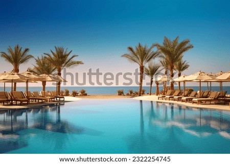 Luxurious beach resort with swimming pool and loungers umbrellas with palm trees Royalty-Free Stock Photo #2322254745
