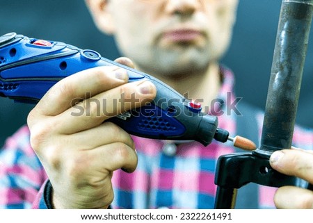 A bicycle mechanic holds a bicycle fork in his hands on a black background. Bicycle repair in the workshop. A mechanic uses a power tool to work.