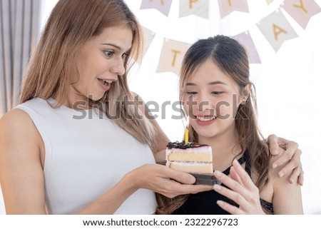 Image of excited happy pretty girls friends holding cake. Beautiful two girls blowing out the candle on a birthday cake. Holiday, happy friend and birthday concept.