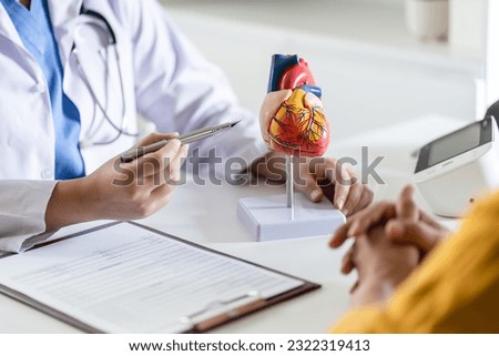 Cardiology Consultation treatment of heart disease. Doctor cardiologist while consultation showing anatomical model of human heart with aged patient talking about heart diseases Royalty-Free Stock Photo #2322319413